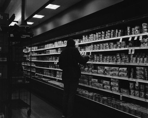 Person reading food labels in a supermarket aisle